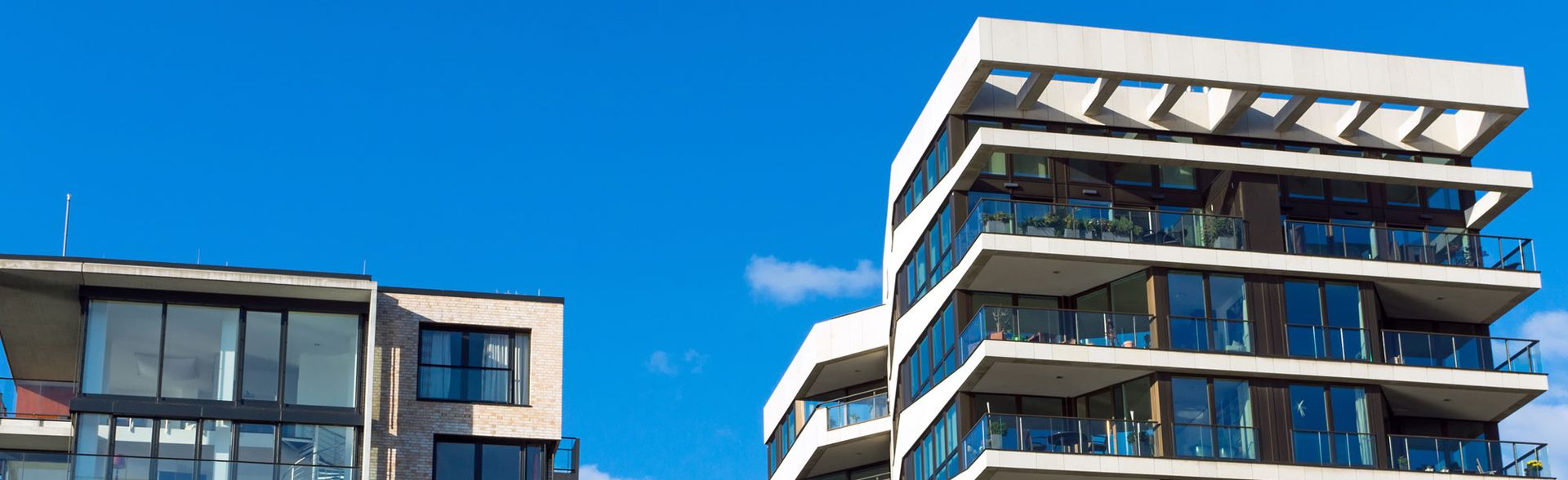Mehrstöckige moderne Wohngebäude mit großen Balkonen vor blauem Himmel